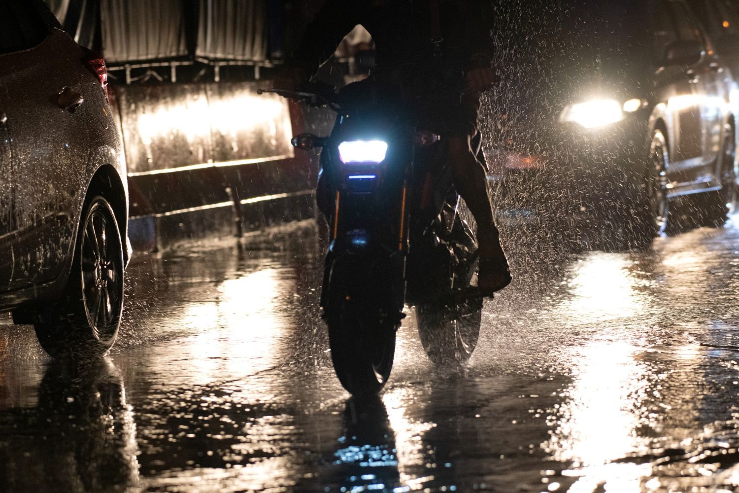 Close-up of motorcycle headlight and rain on Las Olas Boulevard at night.