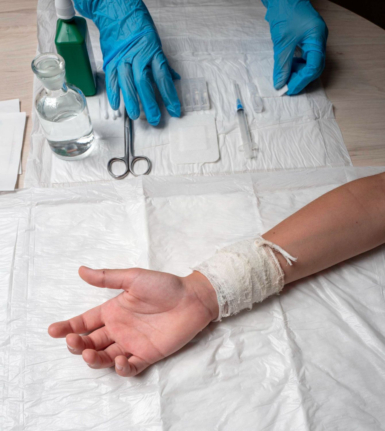 Bandaged hand resting on a polished table with silver medical scissors nearby