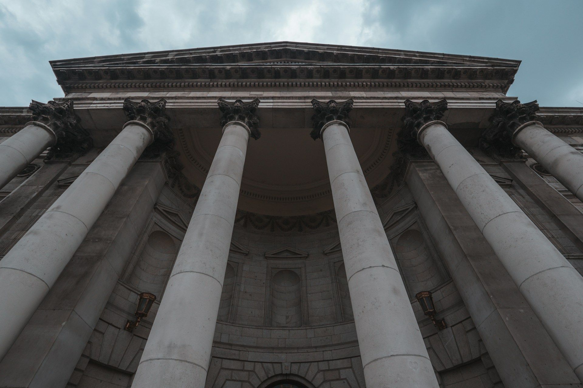 Stone building facade with tall columns under a cloudy sky.