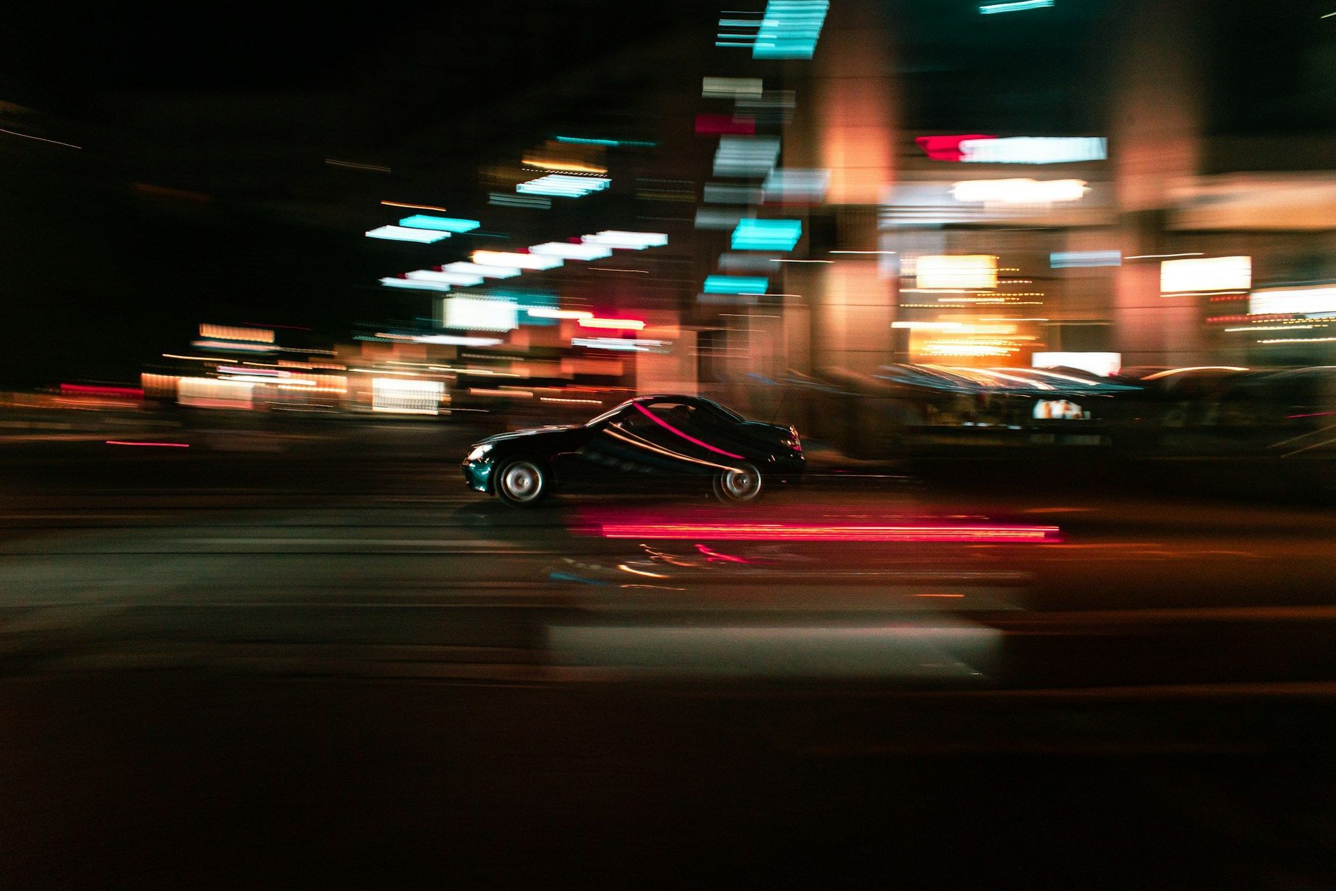 Black car speeding at night, blurred lights of buildings and headlights.