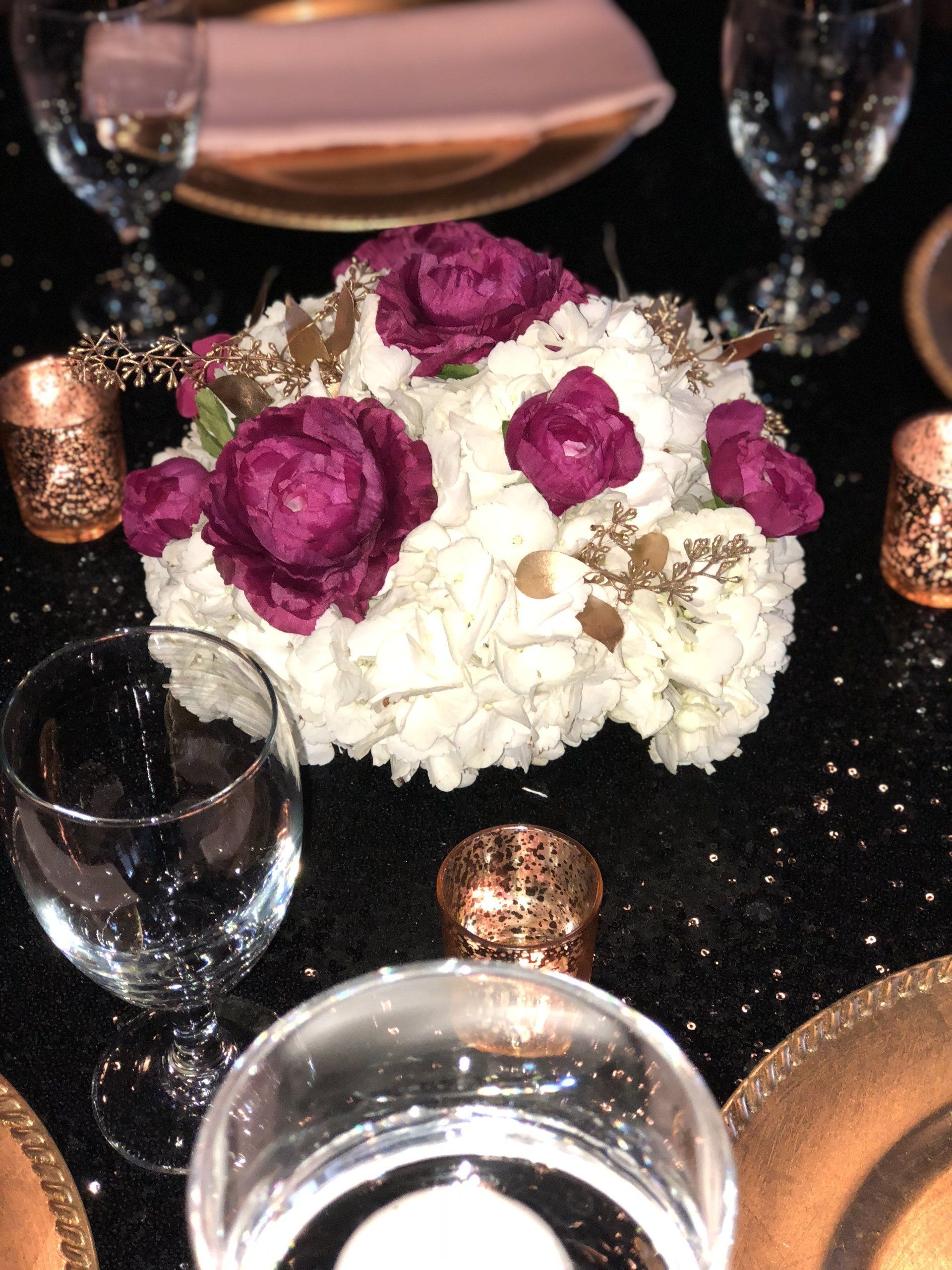 Multi-flower centerpiece with gold accents complemented by gold tea-light candle holders.