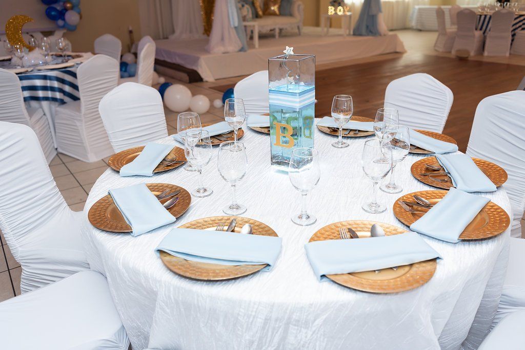 Closeup of a custom table design with a square tall vase filled with blue water, a striped blue ribbon, an initial 