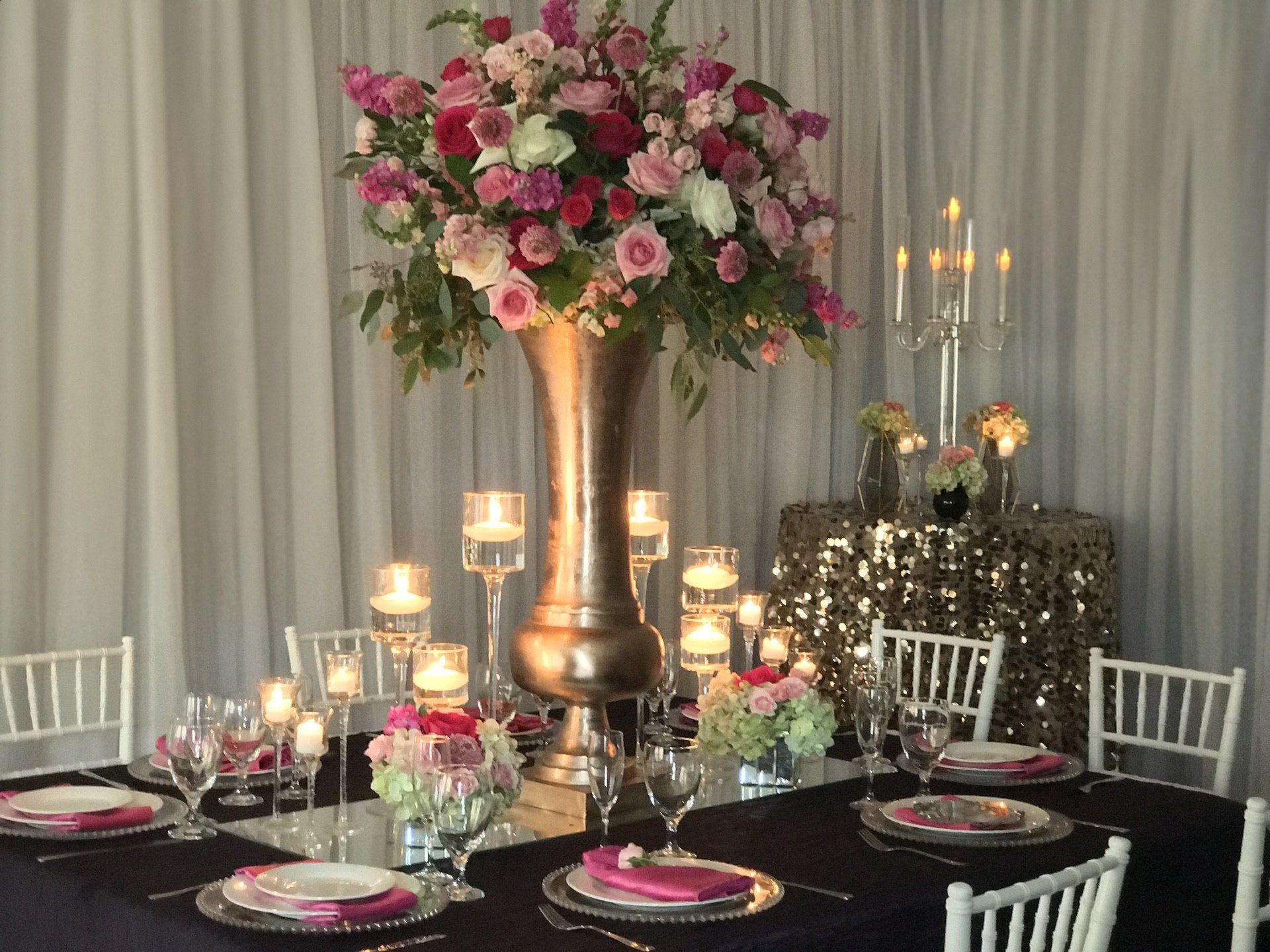 An event table design with a multi prop and bouquet centerpiece. Focal point is an elegant bouquet in a tall vase.