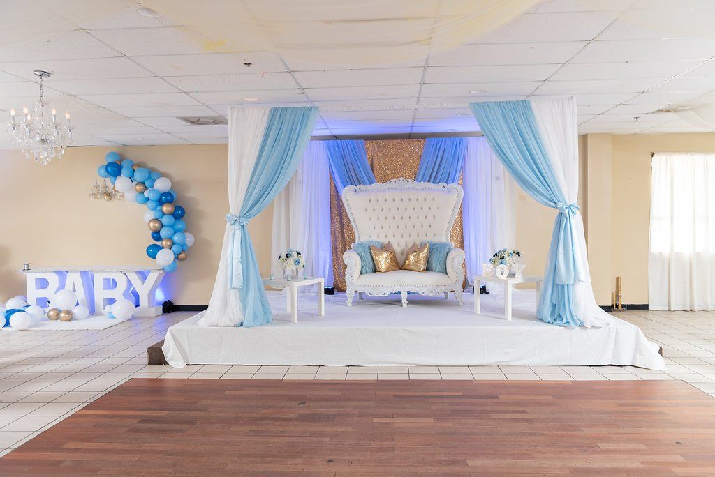 A raised stage setup for a baby shower with a custom designed multi layered draped backdrop.
