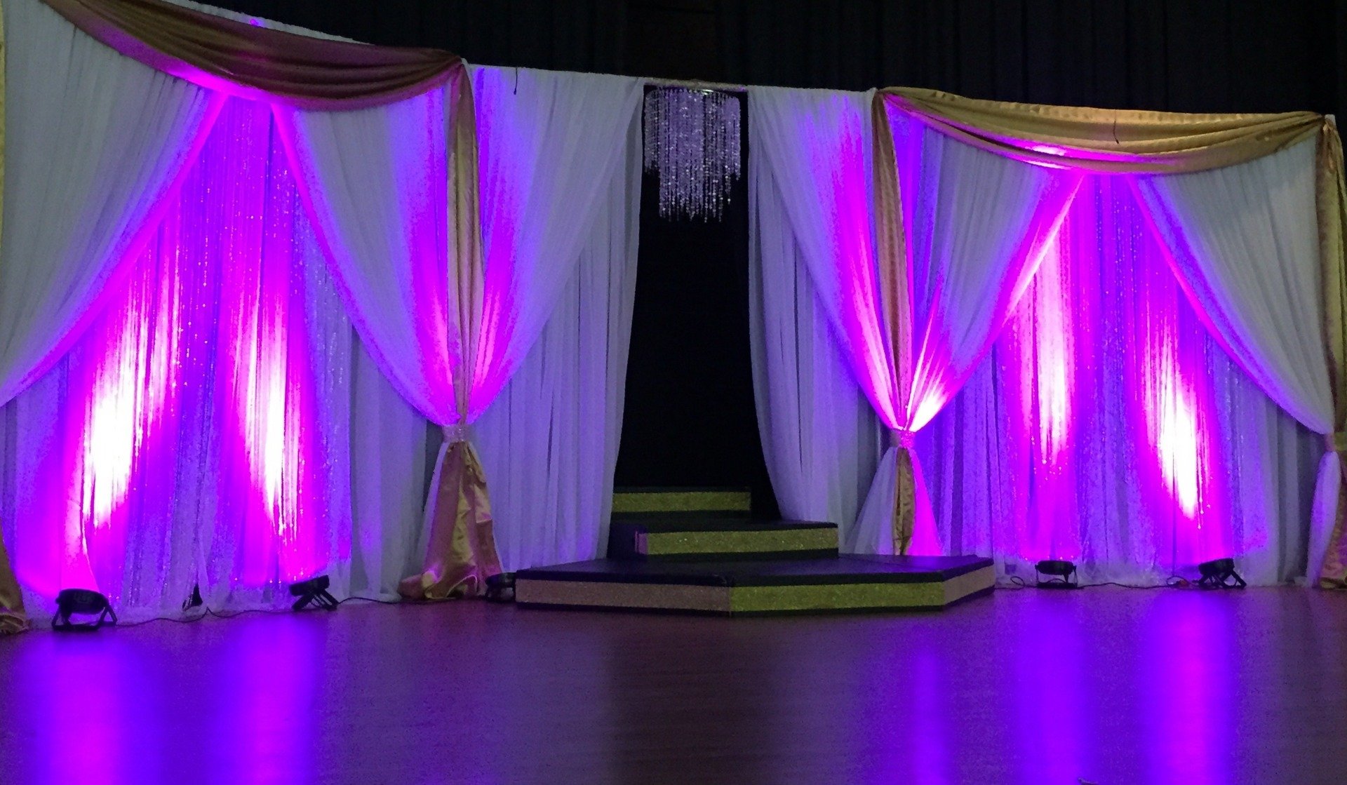 Custom backdrop draping with uplighting and an entrance in the center.