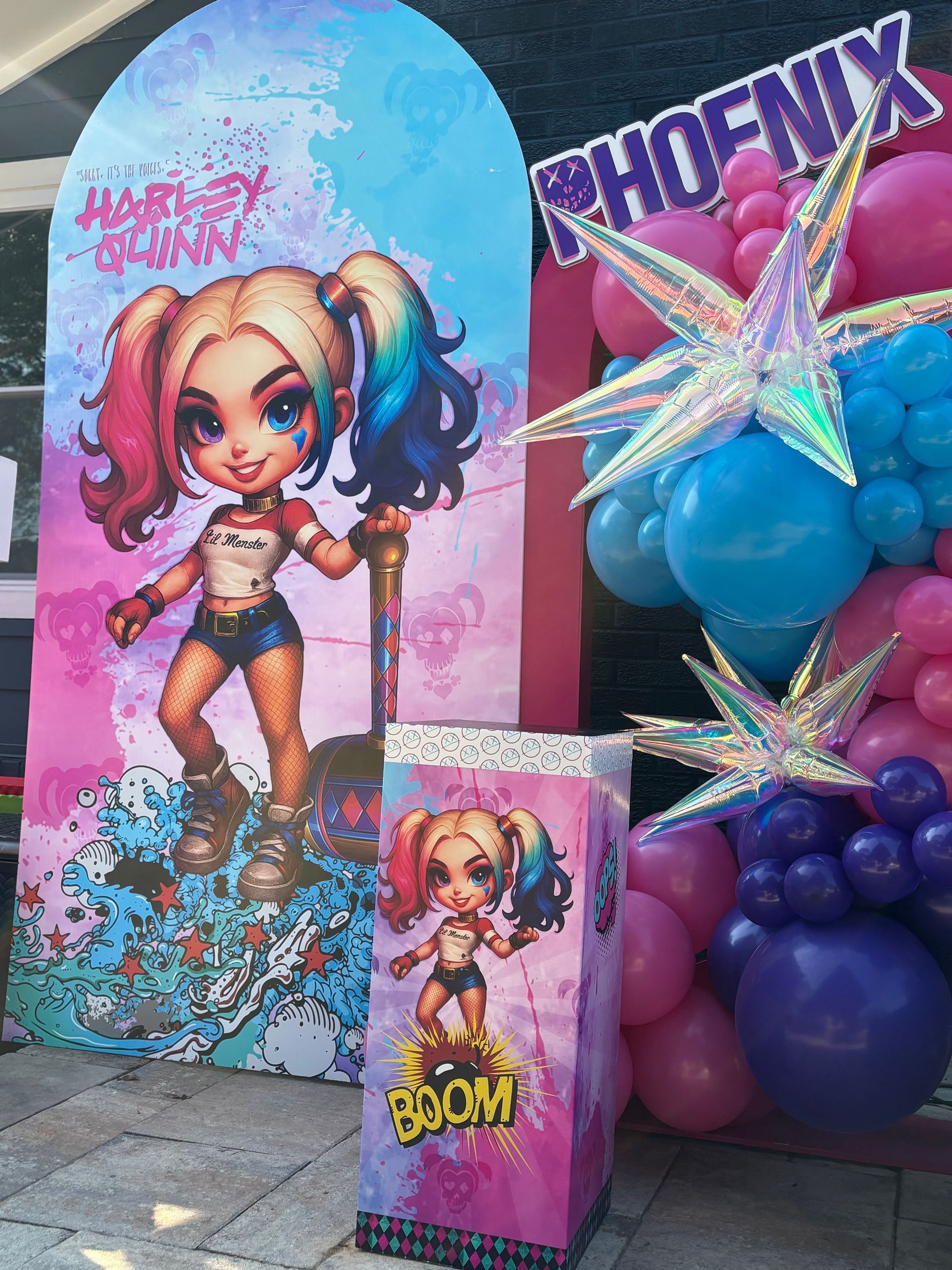 Close-up of Harley Quinn inspired custom party backdrop with bright balloons and star accents for superhero girls birthday