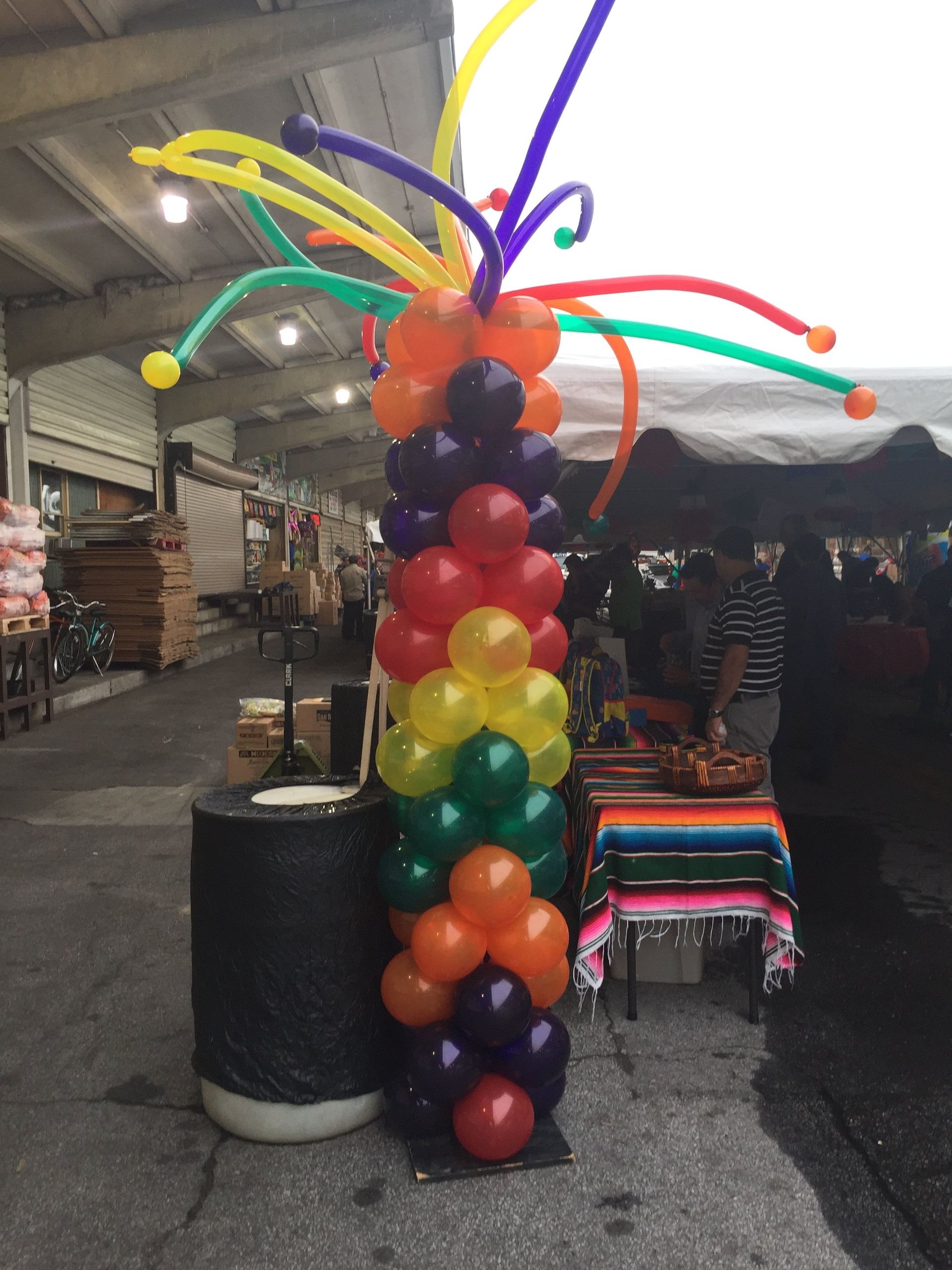 A festive column with strip balloons bursting out of the top in multiple colors.