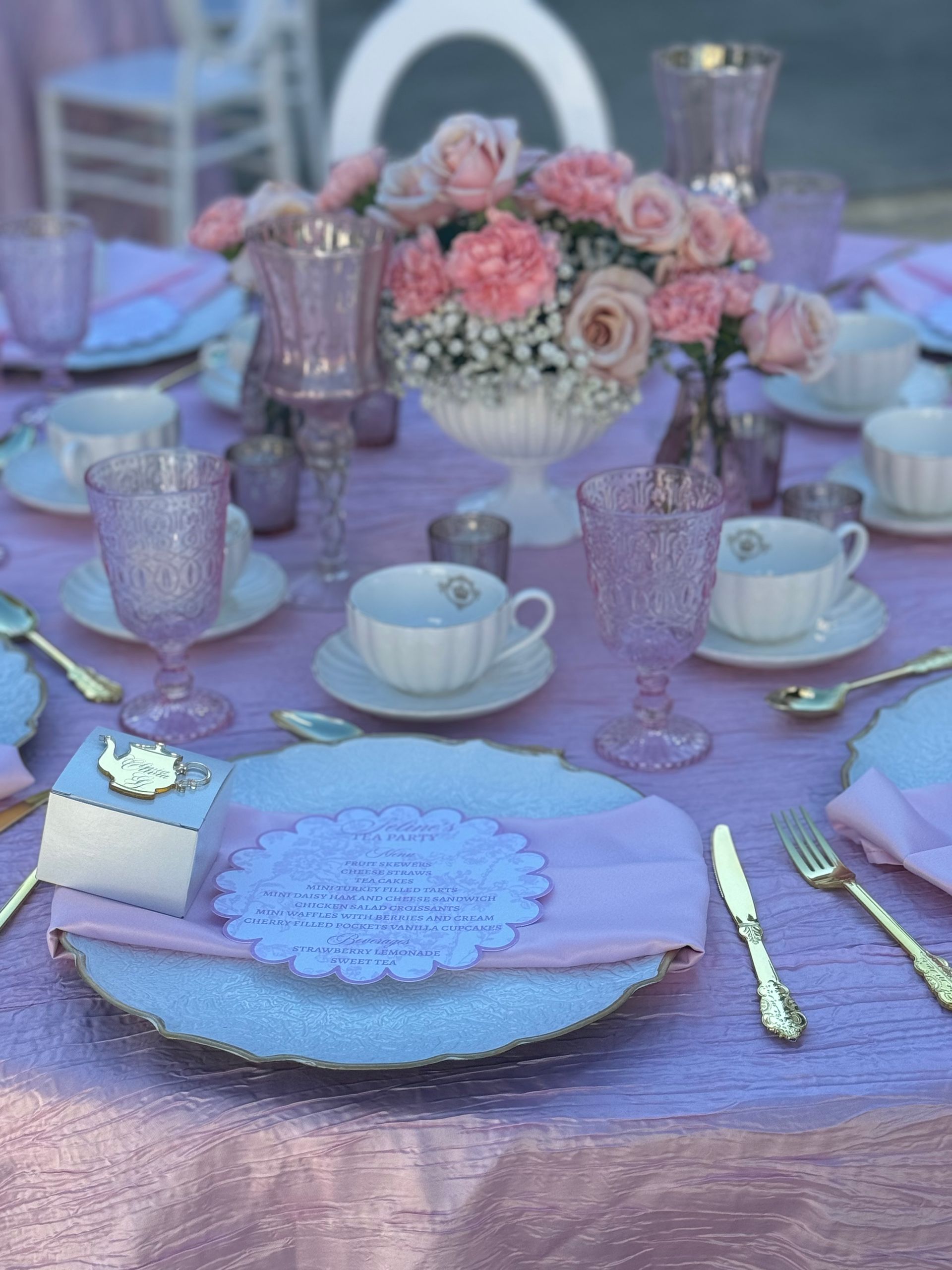 Pastel kids party table setup with floral centerpieces, soft linens, and elegant tea party place settings