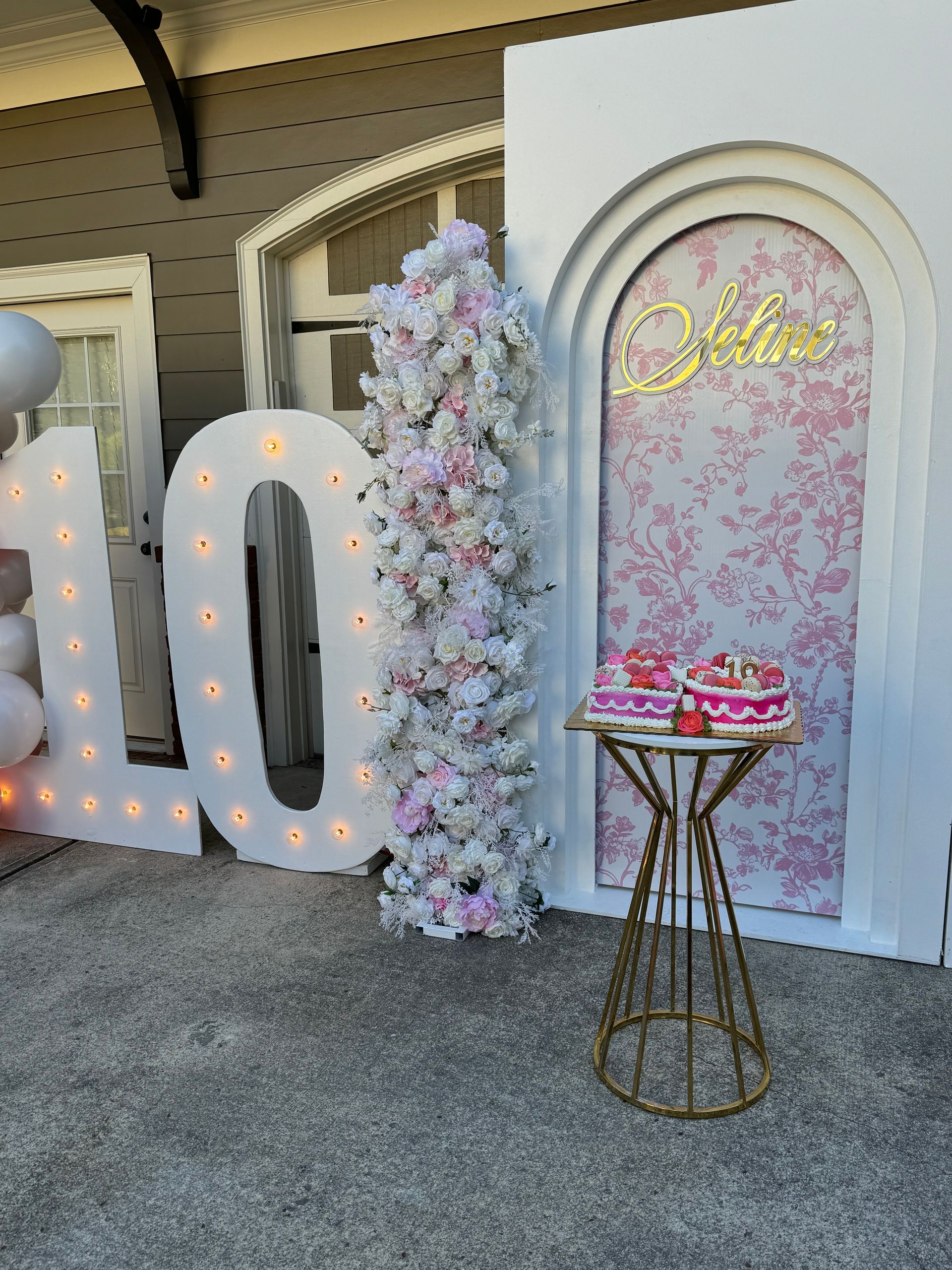 Custom kids party backdrop with floral wall, pastel balloons, and personalized name sign for birthday photos