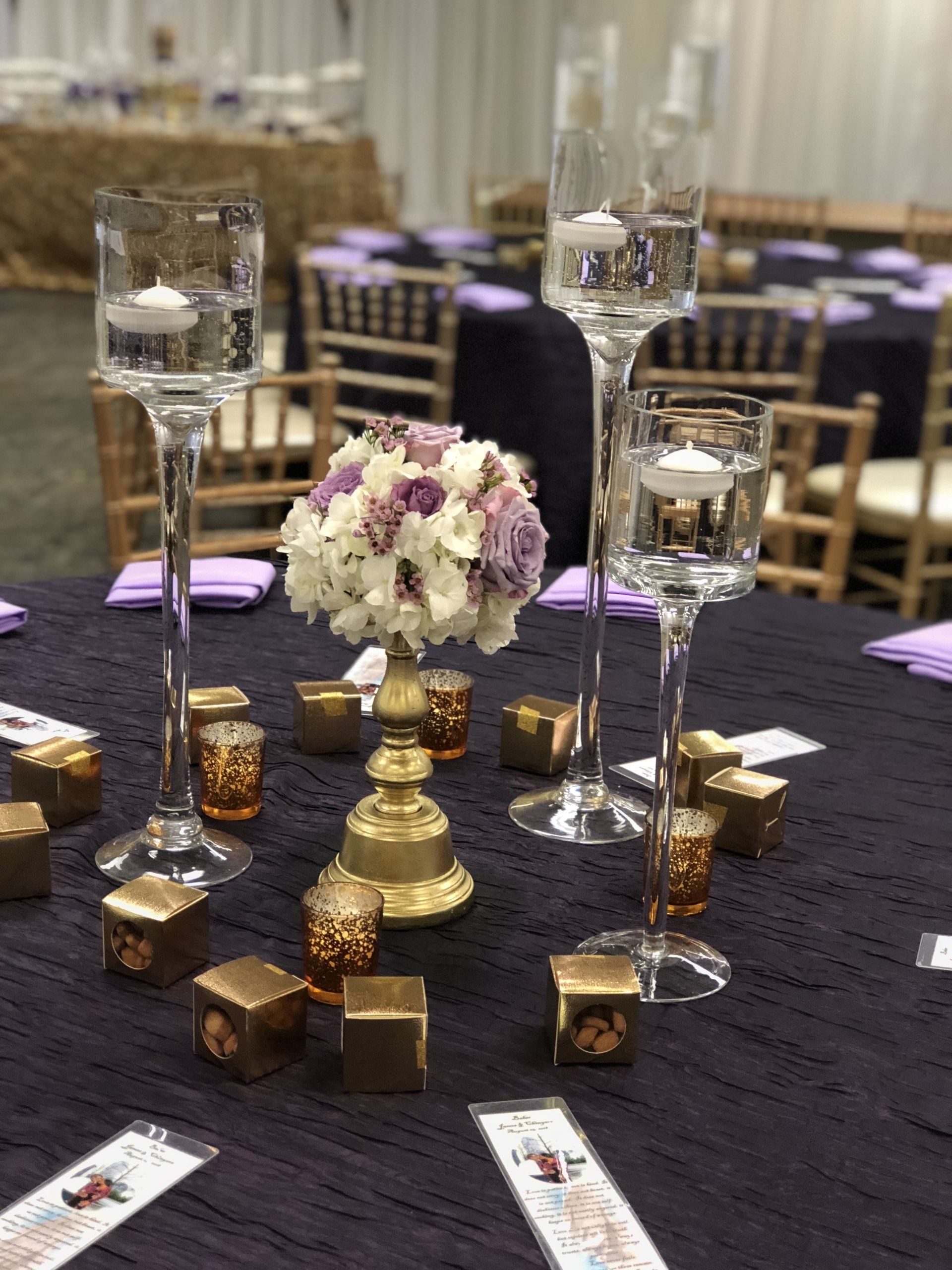 Floral centerpiece with floating candles in tall stem holders.