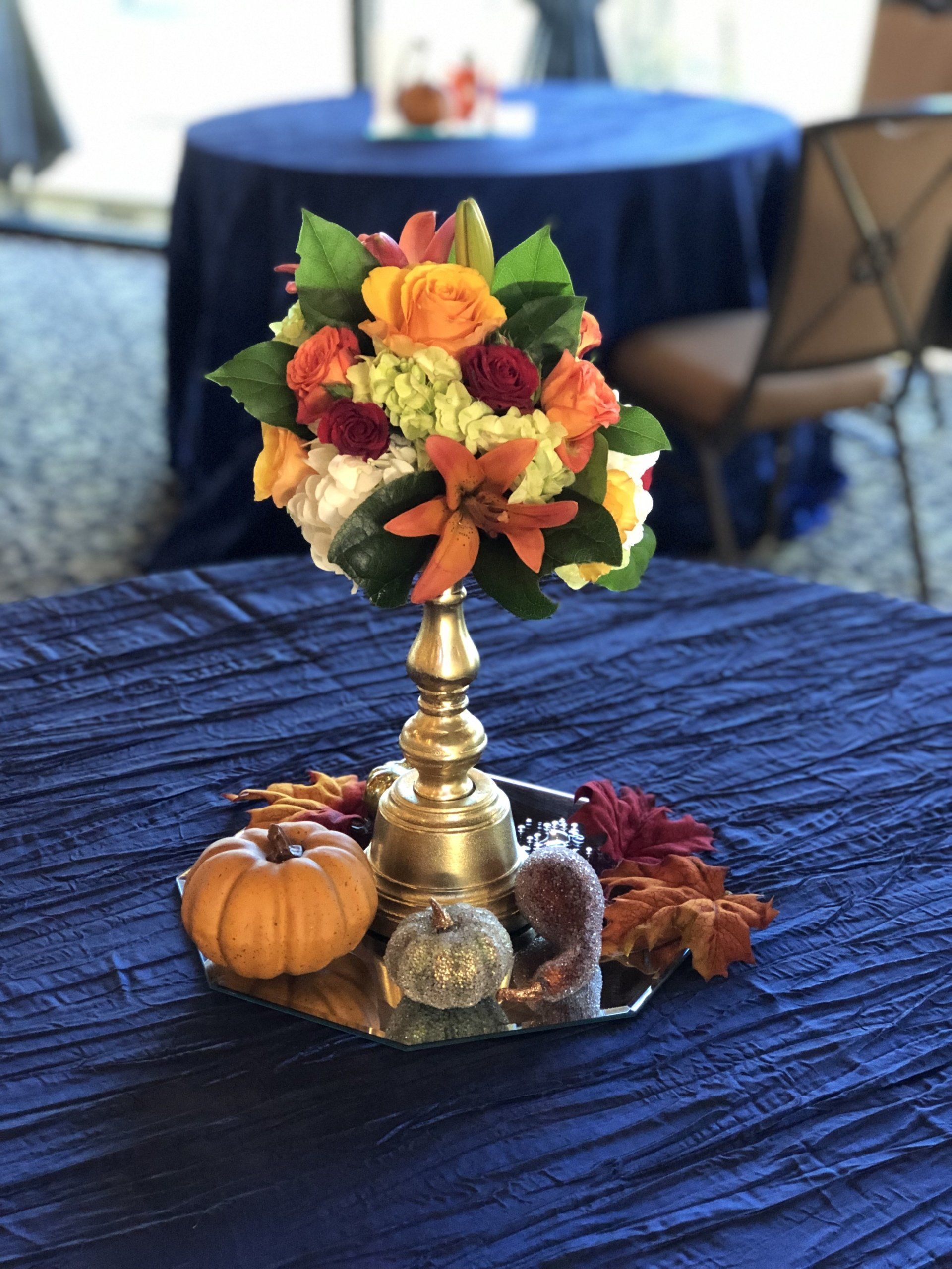 Fall themed centerpiece with pumpkin and leaf accents.