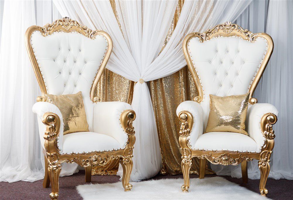 Prestige thrones with gold trim and accent pillows. Multi layered draping design in the background.