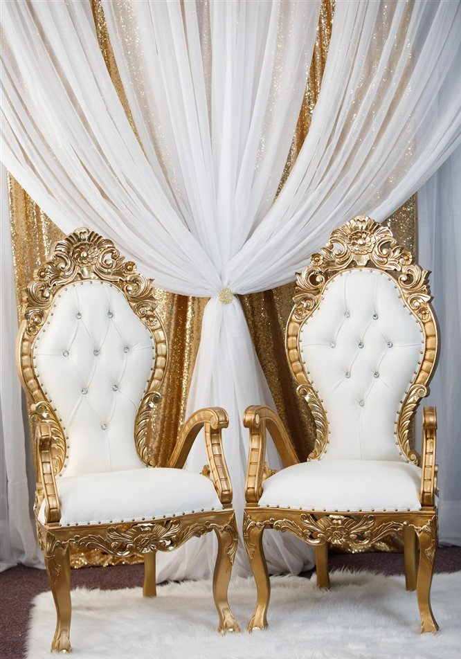 Venus thrones with gold trim and multi layered draping in the background.