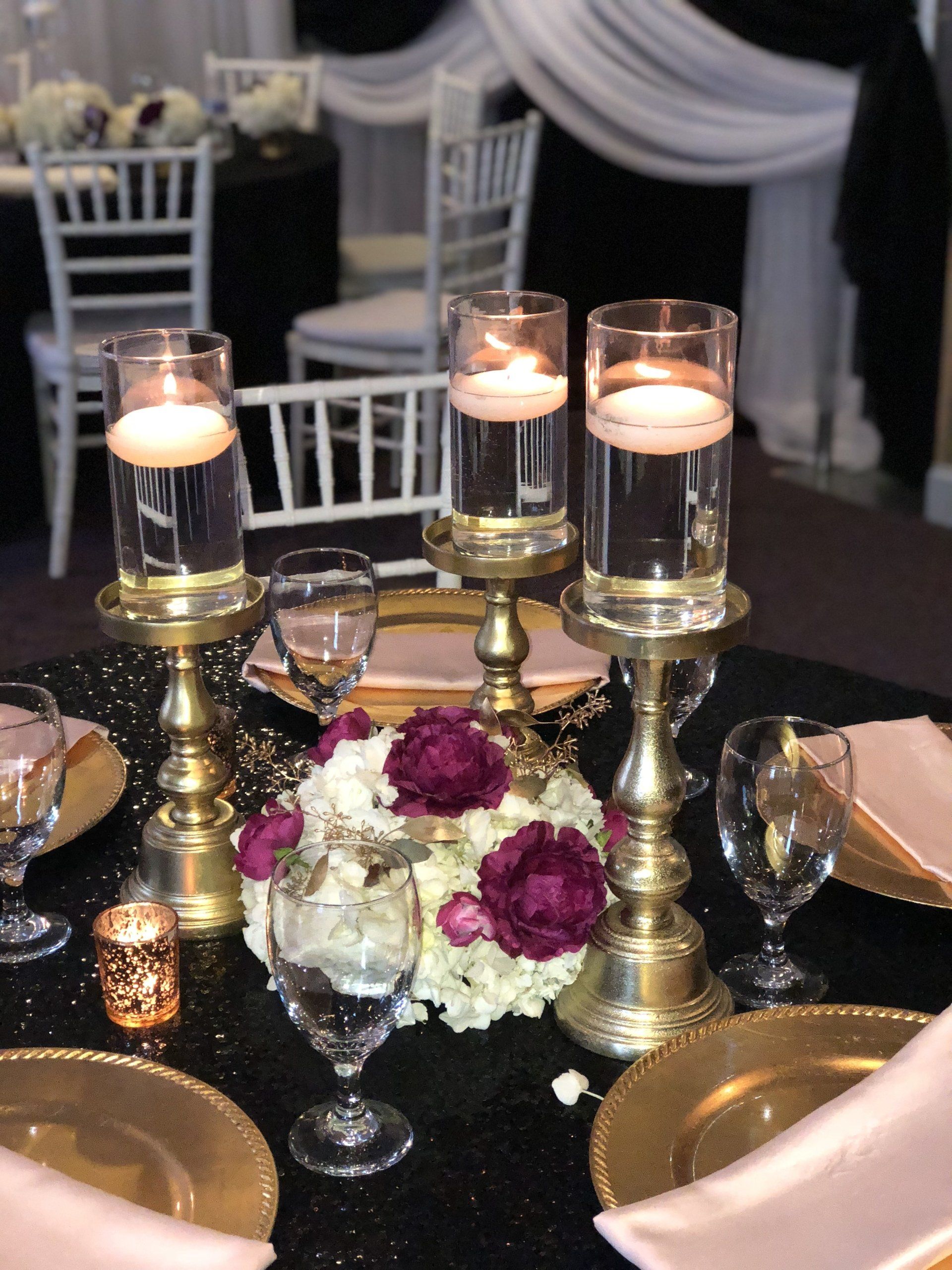 Centerpiece design with three floating candle holders sitting on elegant pedestals and a floral display in the center.