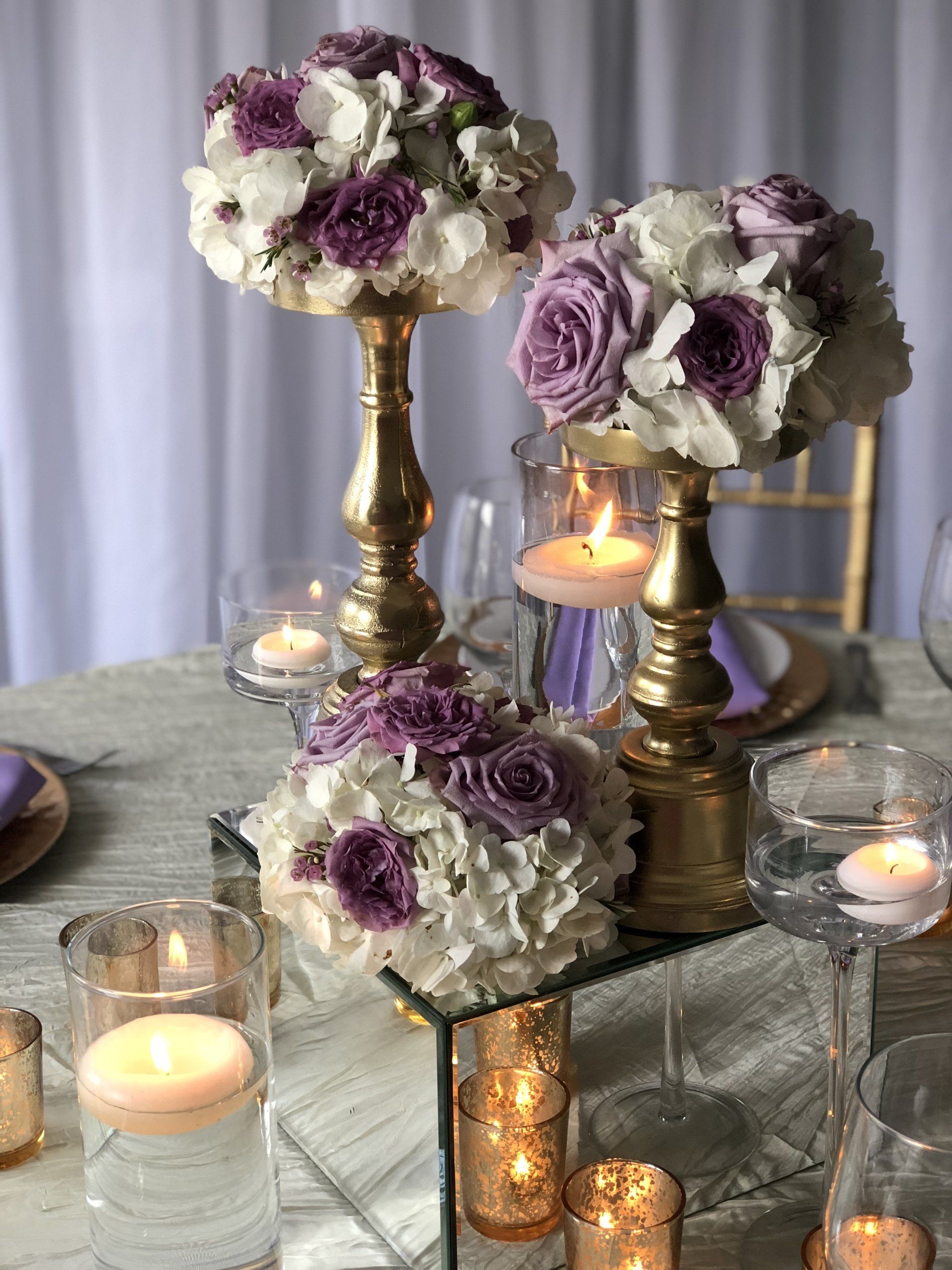 Centerpiece designed with multiple elements including vases of varying heights and candles.