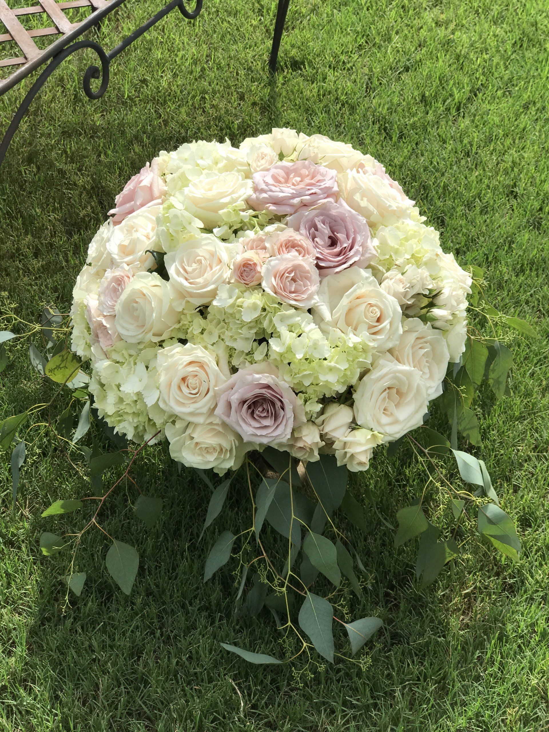 Large floral arrangement with leaf accents sitting on green grass.