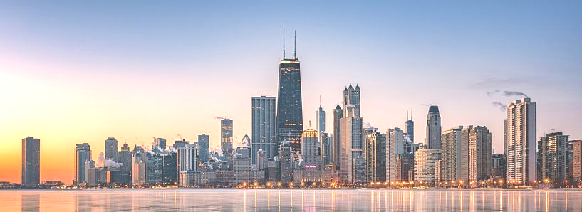 Chicago skyline at dawn, with tall buildings reflecting in the water.