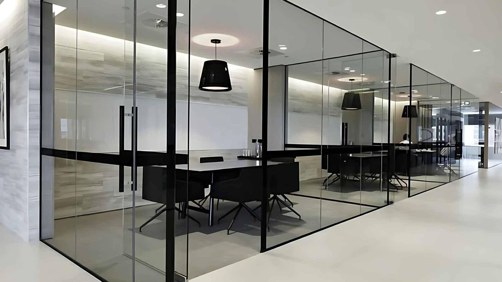 A modern office conference room with glass walls, black furniture, and white walls.
