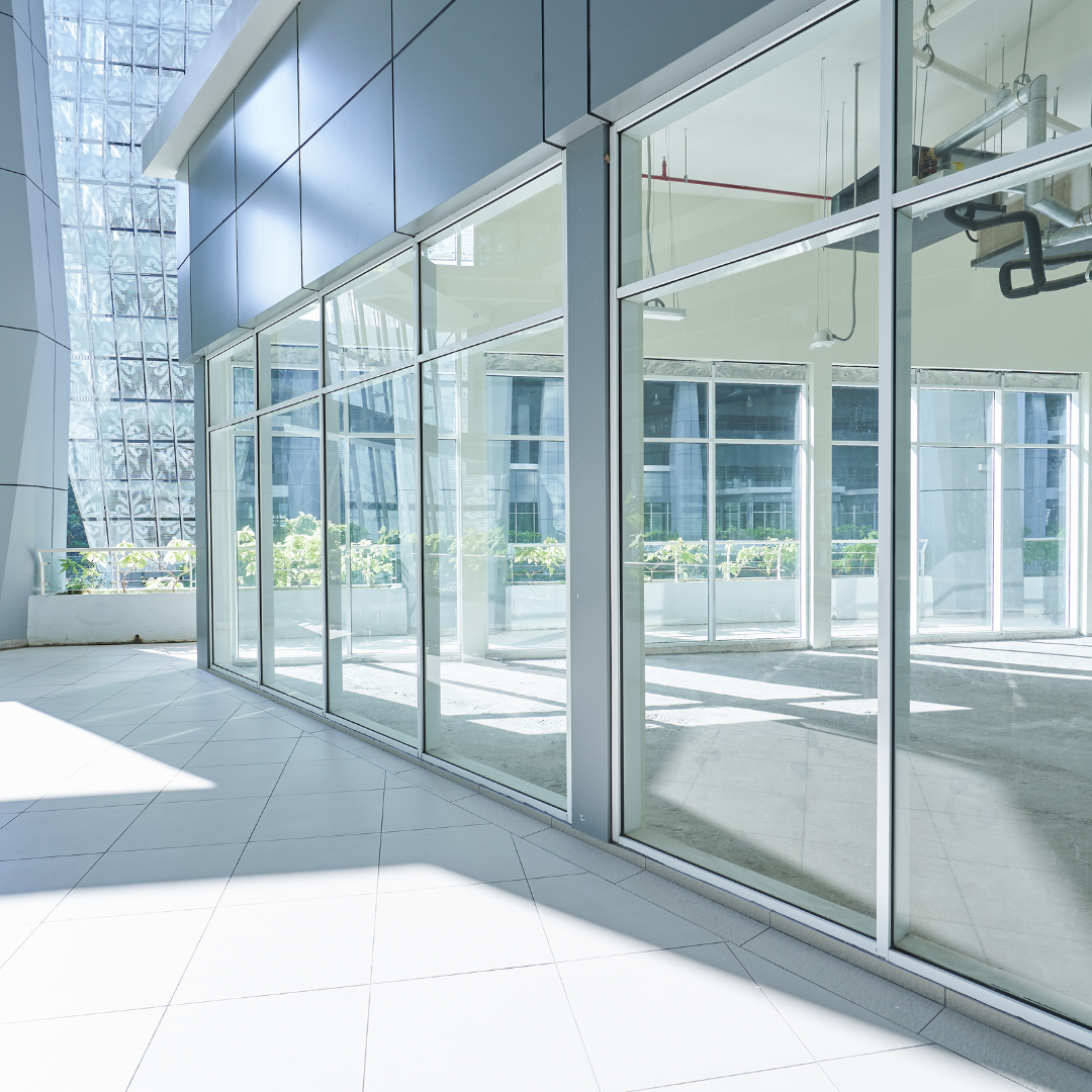 Bright, modern building exterior with a long row of glass windows, reflecting the sky and interior space.