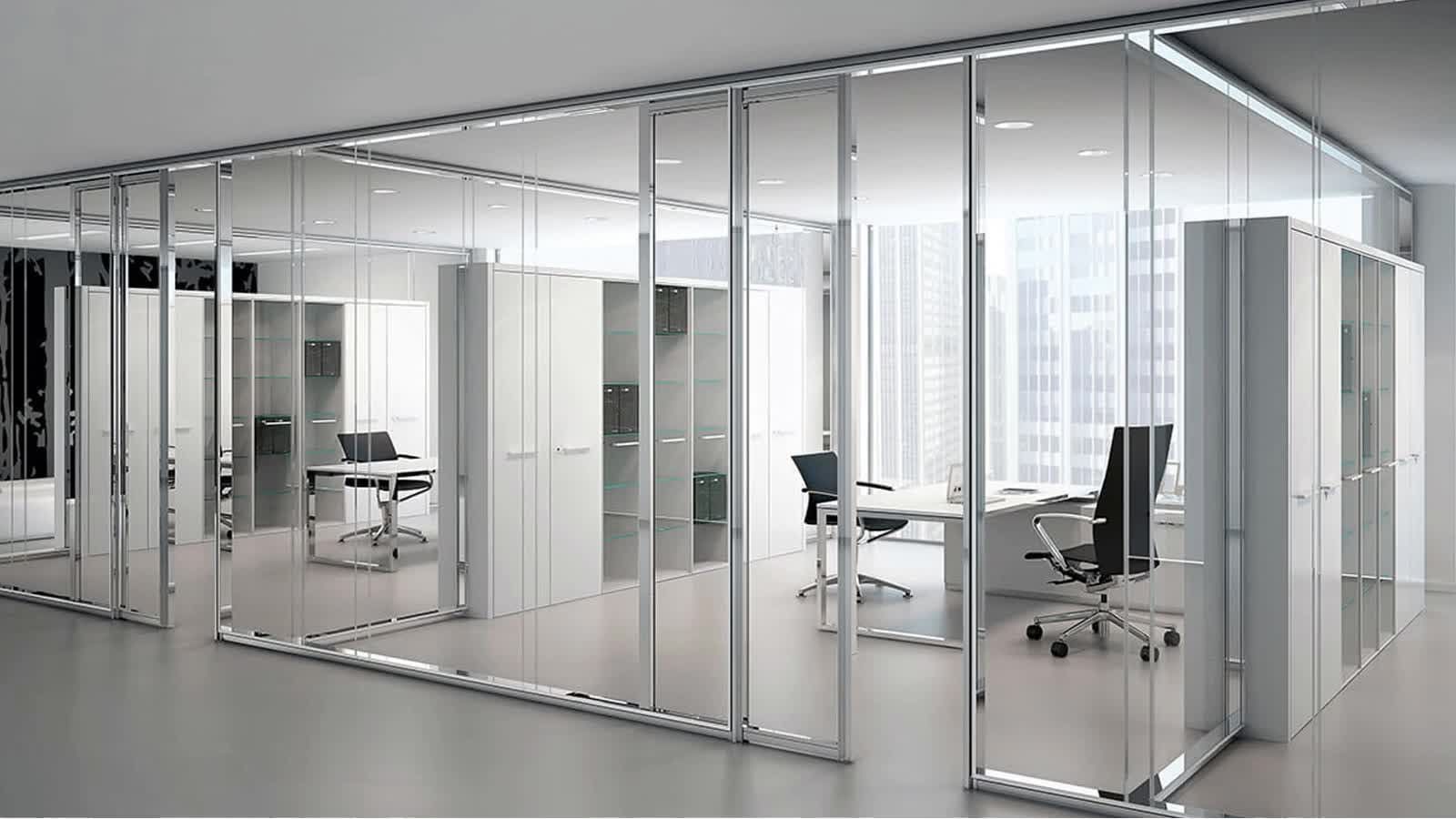 Modern office space with glass panel walls, showcasing individual offices with desks and chairs.