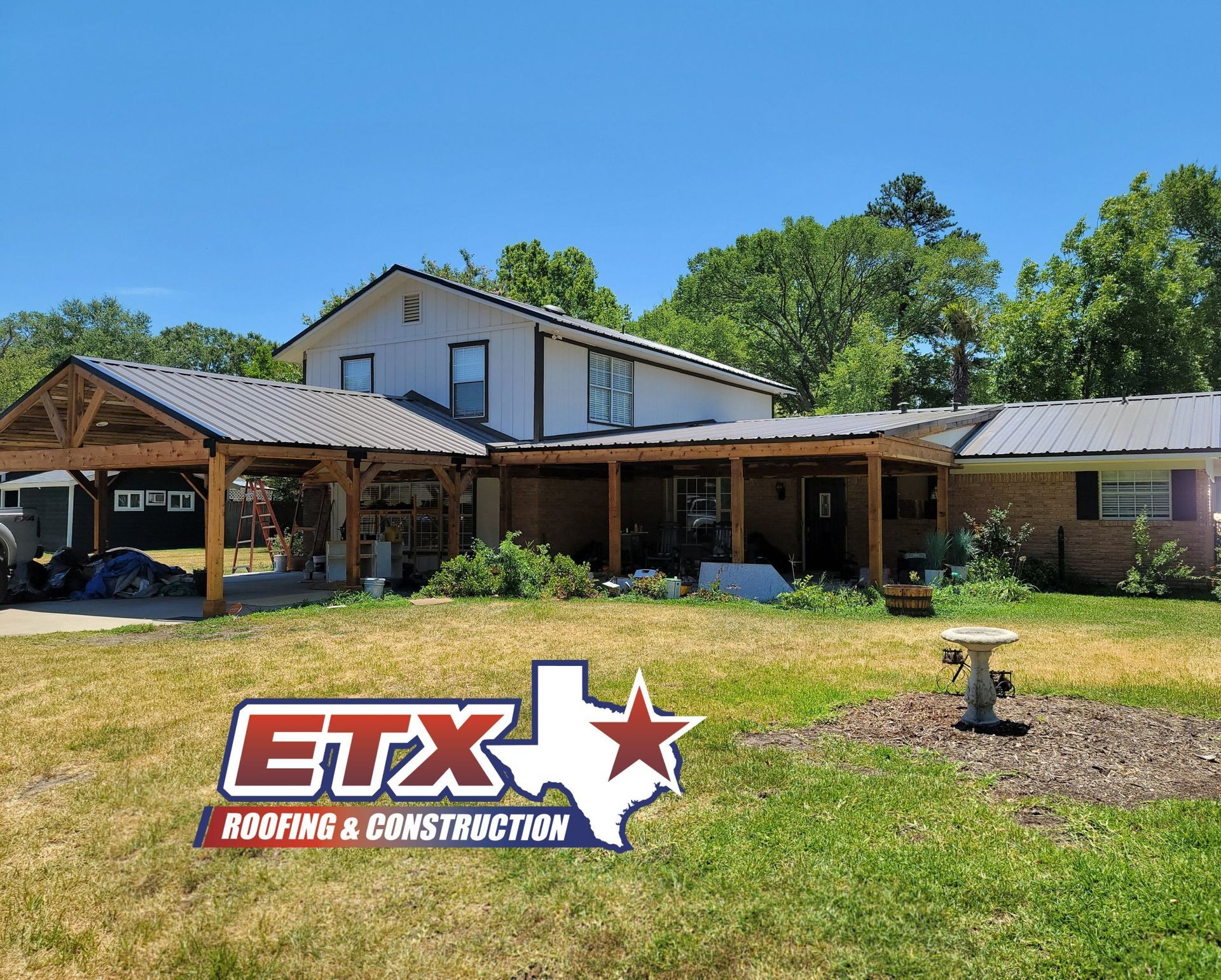 A large house with a porch and a sign that says etx roofing and construction
