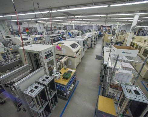 Assembly line in a manufacturing facility with white machinery and workstations, likely electronics.