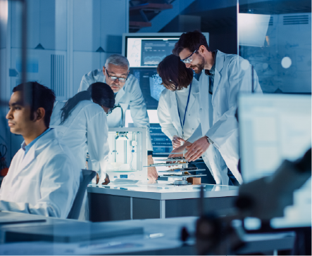 Scientists in lab coats collaborate around equipment in a modern laboratory, focused and analyzing data.
