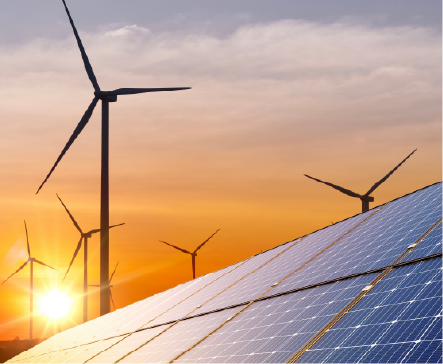 Solar panels in foreground with wind turbines at sunset.