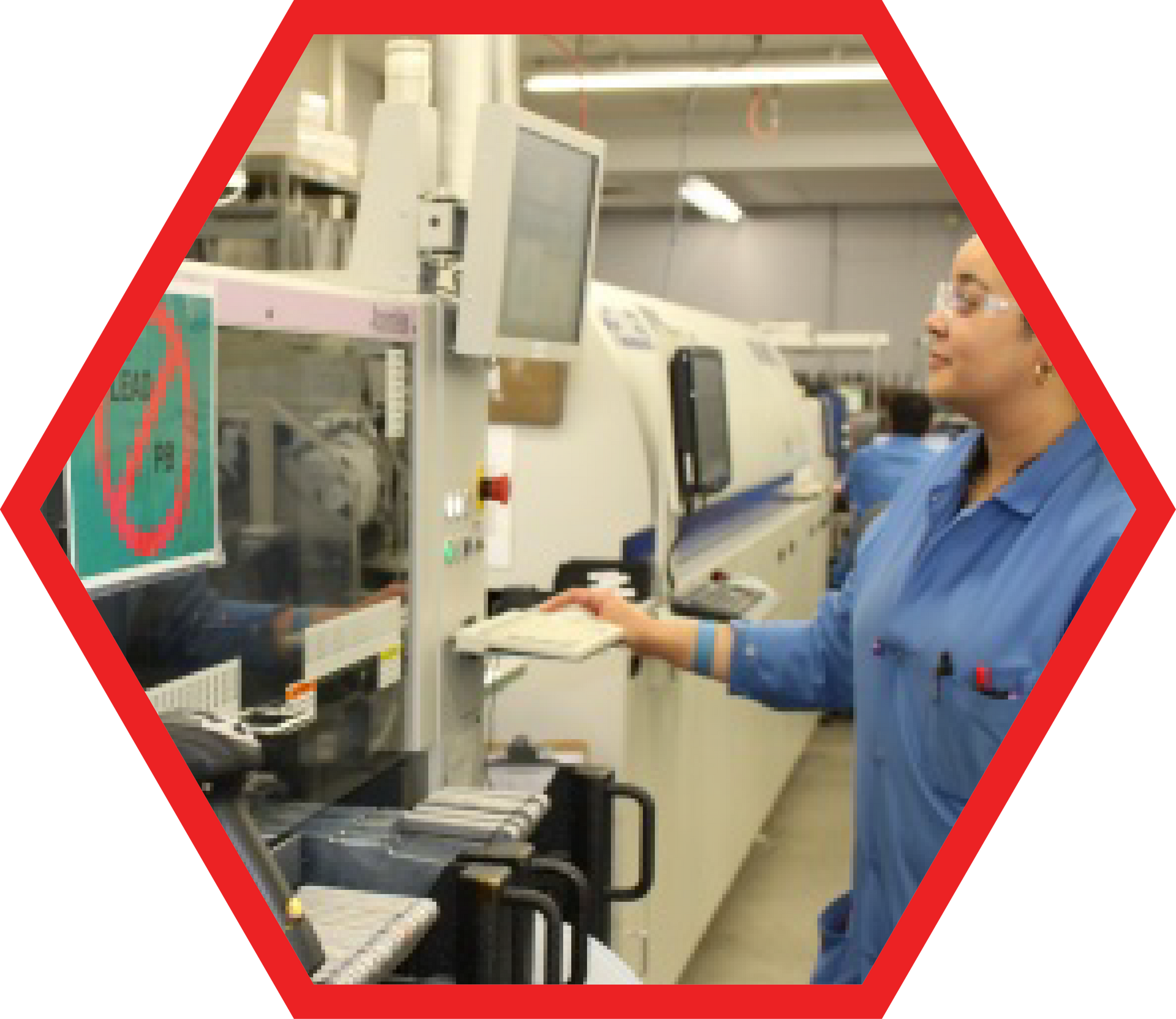 Woman in blue uniform operating machinery in a factory; large machine in the background.