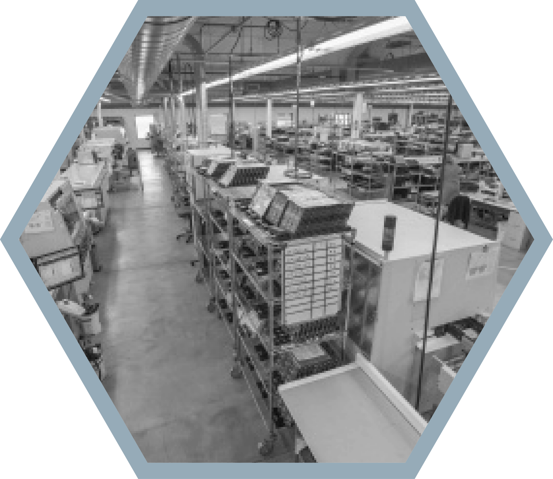 Assembly line in a large industrial warehouse, featuring workstations and workers.