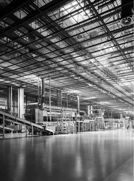 A vast industrial factory interior, machinery, and conveyor belts under a grid ceiling.