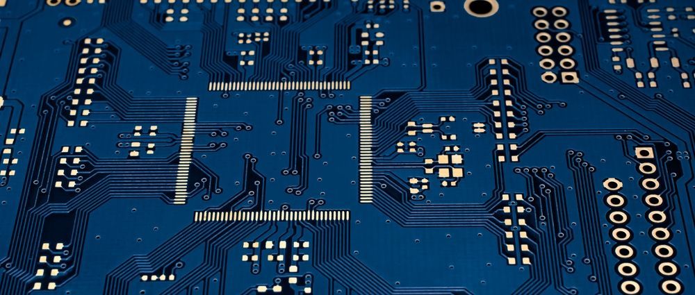 Close-up of a blue circuit board with white components and traces.