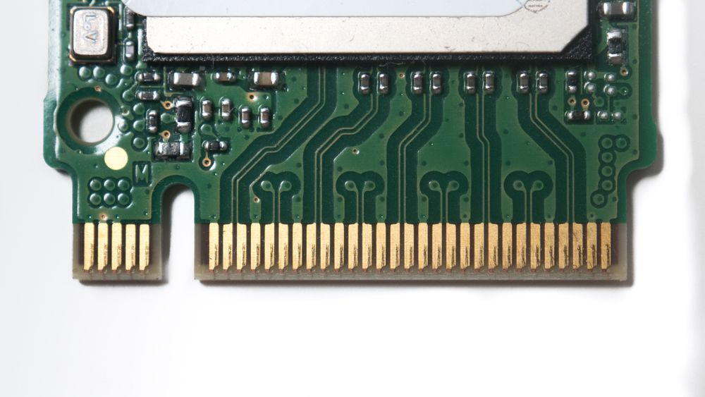 Close-up of a green circuit board with gold connectors on a white background.