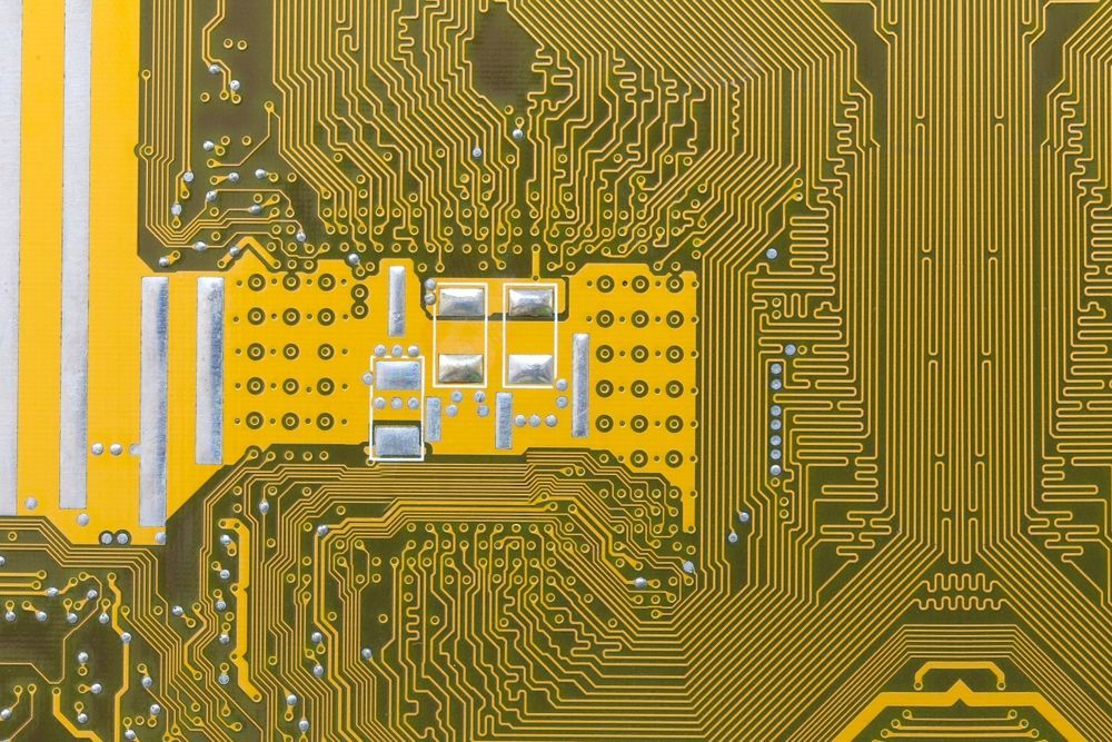 Close-up of a printed circuit board with yellow and gold electrical pathways and components.
