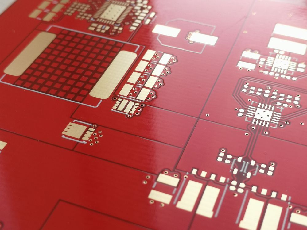 Red circuit board with gold-colored traces and components.