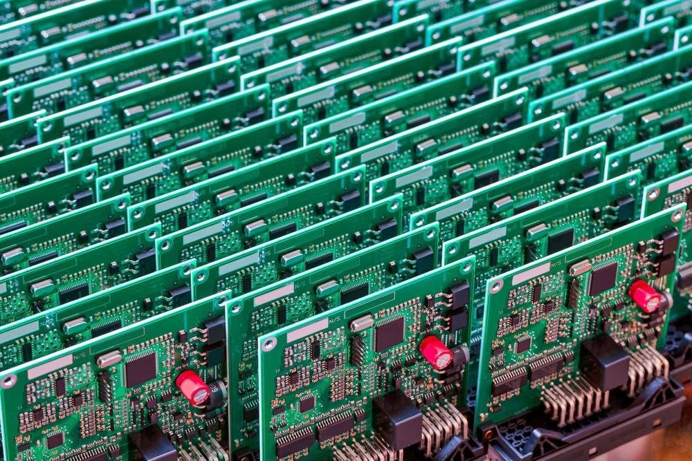 A bunch of green circuit boards are stacked on top of each other on a table.
