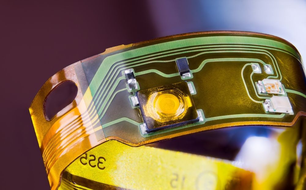 Flexible circuit board with yellow components and green traces.