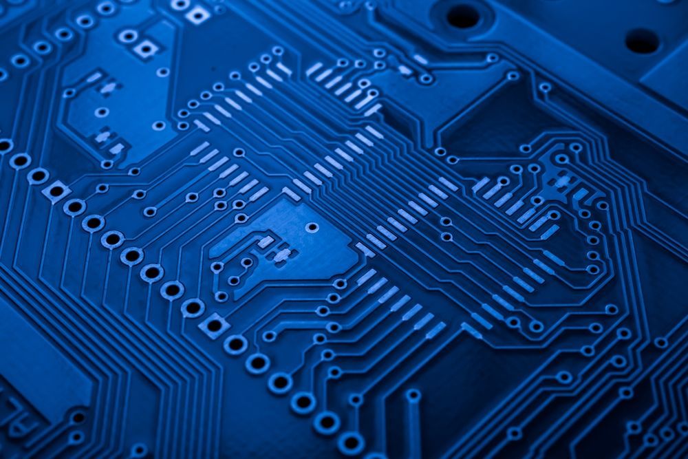 Blue electronic circuit board with intricate pathways and components.