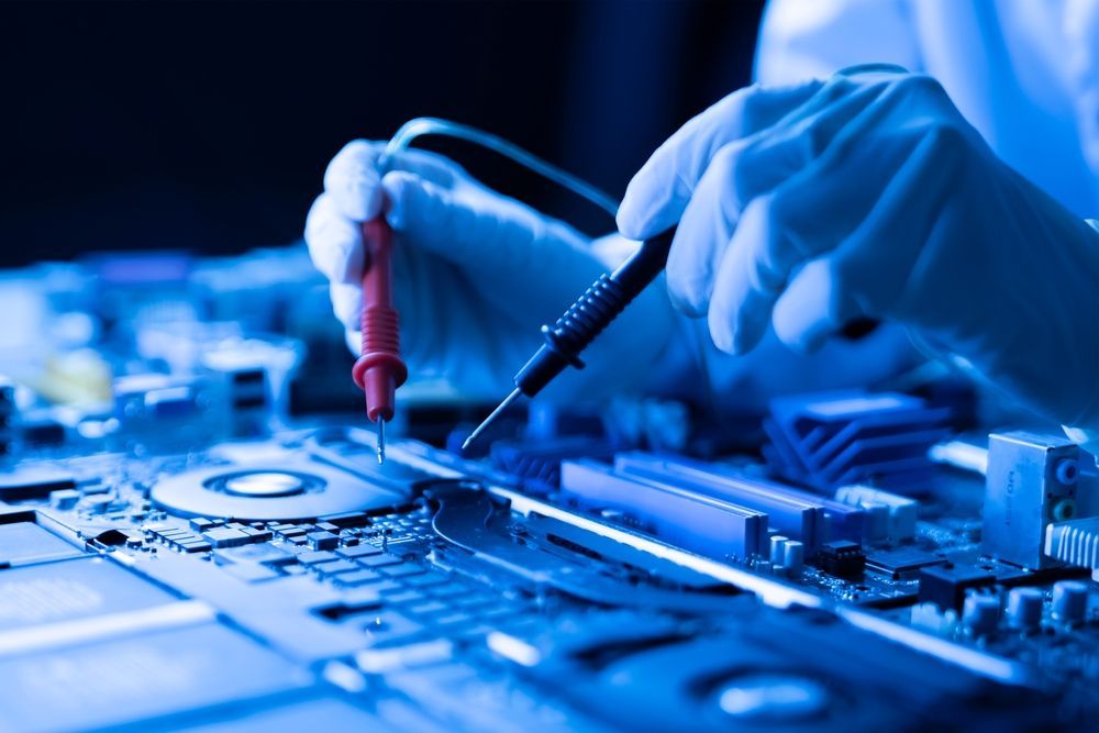 Hands in gloves test a circuit board with probes. Blue-toned lighting.