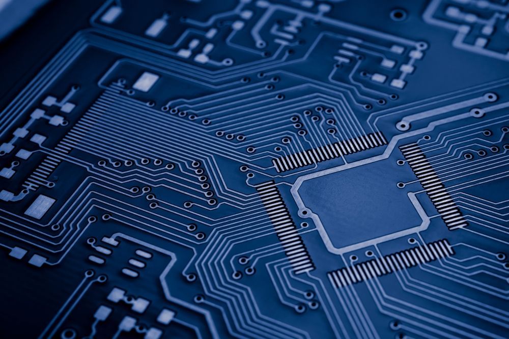 Close-up of a blue circuit board with a central square processor chip.