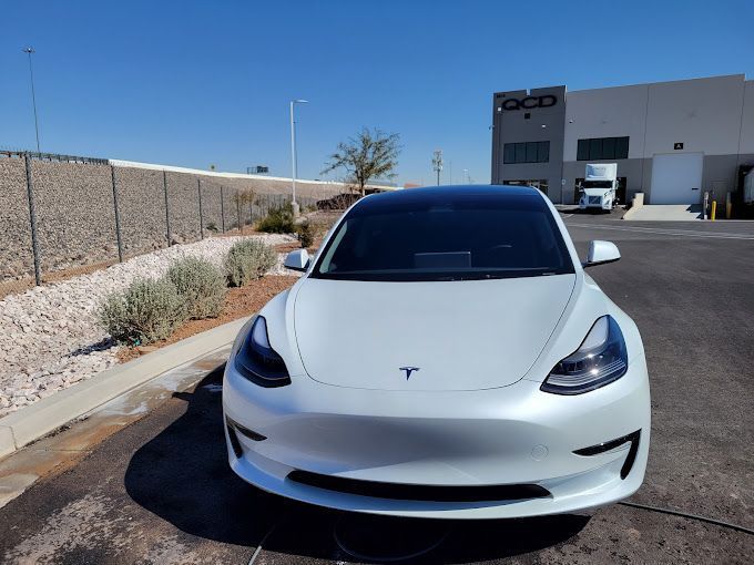 White Tesla Model 3 parked in front of a building with