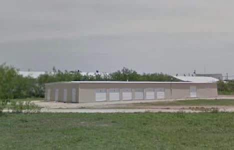 A large building is sitting in the middle of a grassy field.