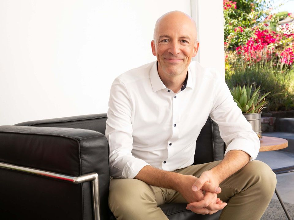 Berkeley therapist Michael Ceely, smiling, seated on a black couch.