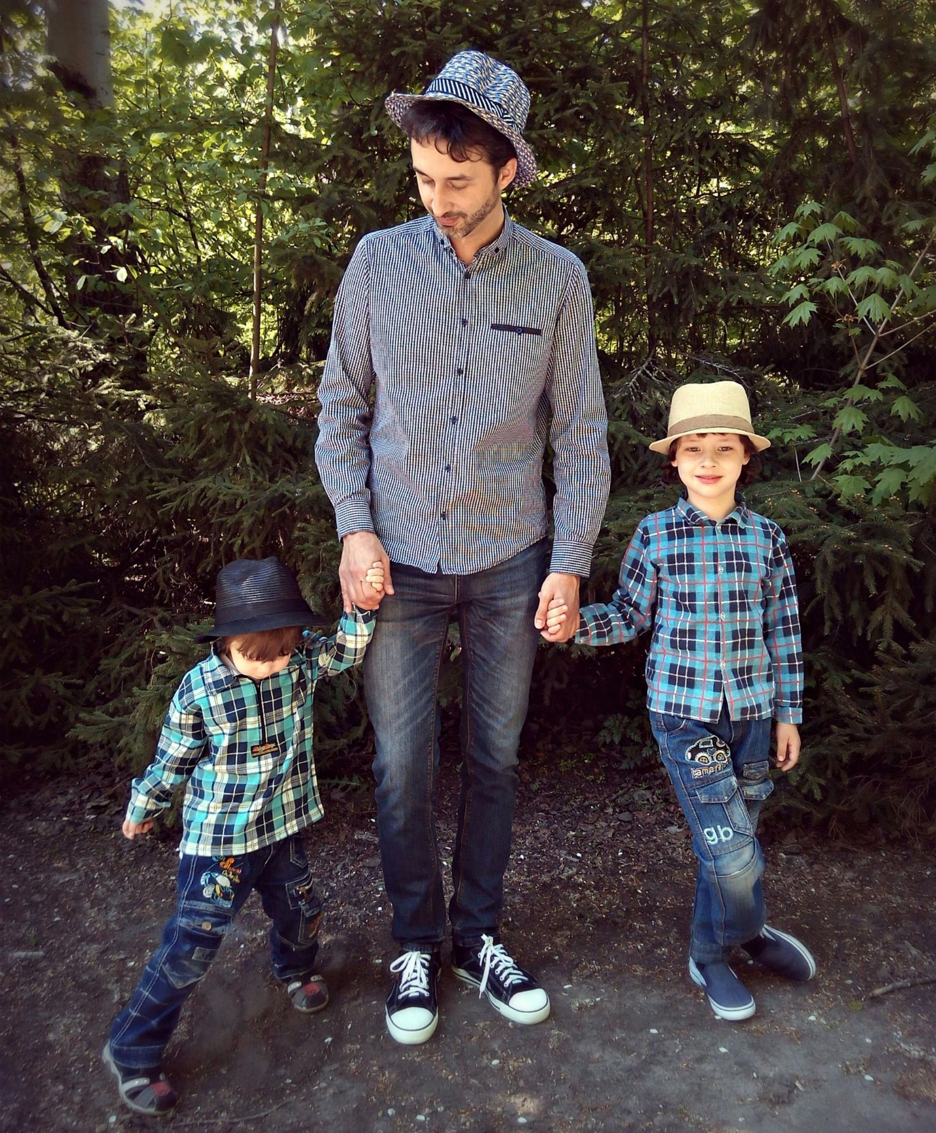 A father and his two children are holding hands in the woods.