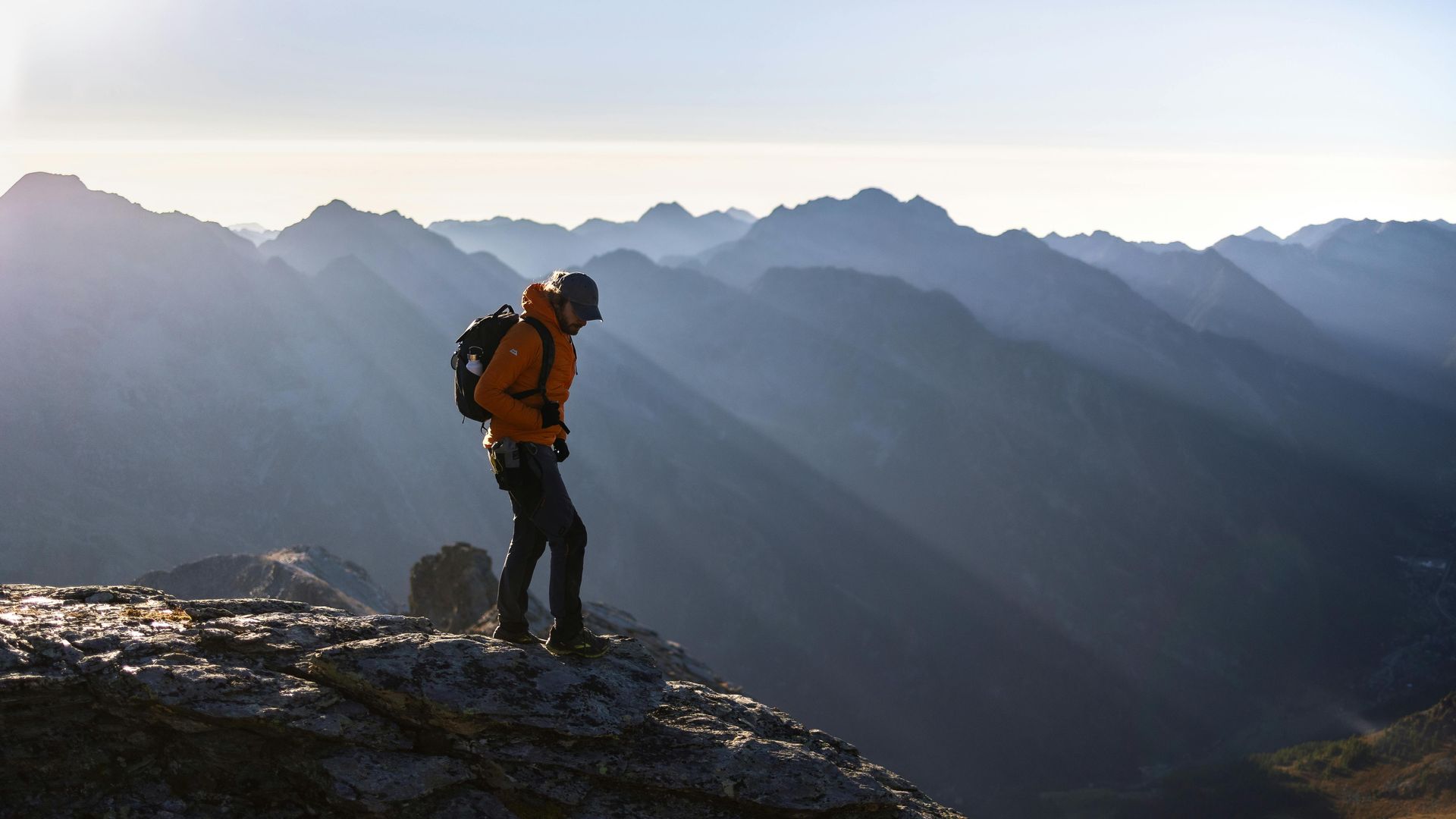 A man with a backpack is standing on top of a mountain.