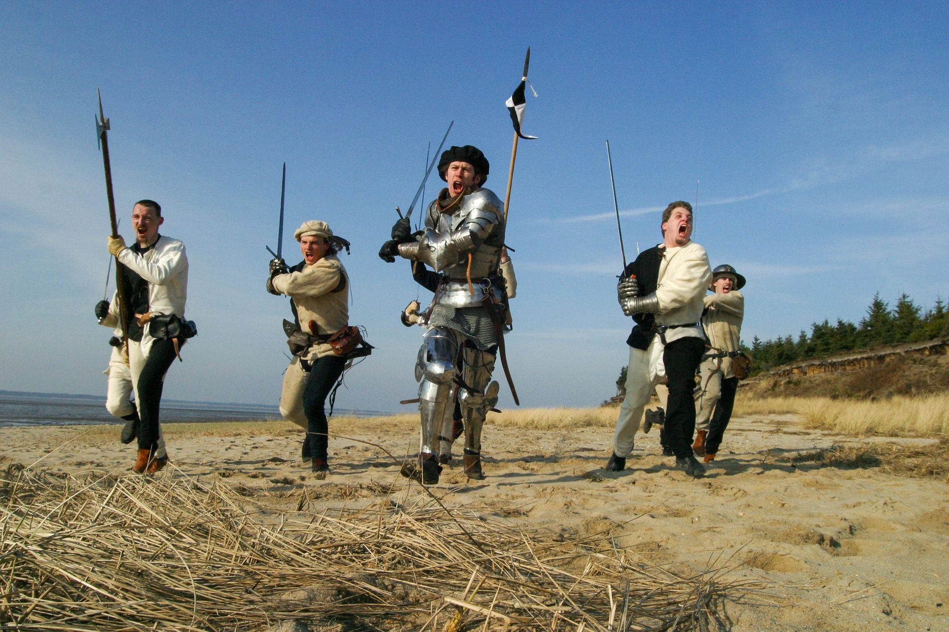 A group of men in armor are walking on a beach
