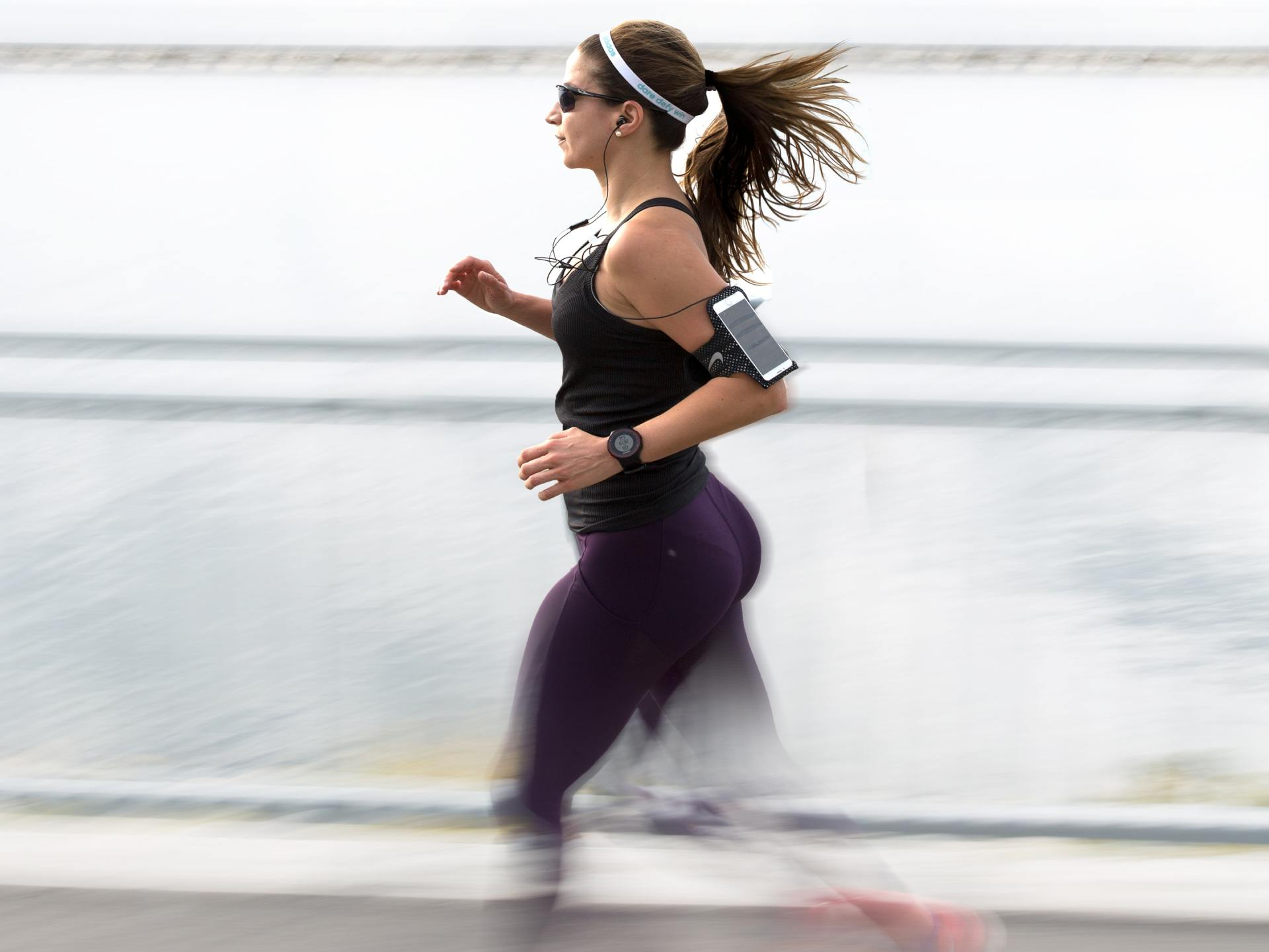Woman running with headphones and a cell phone.