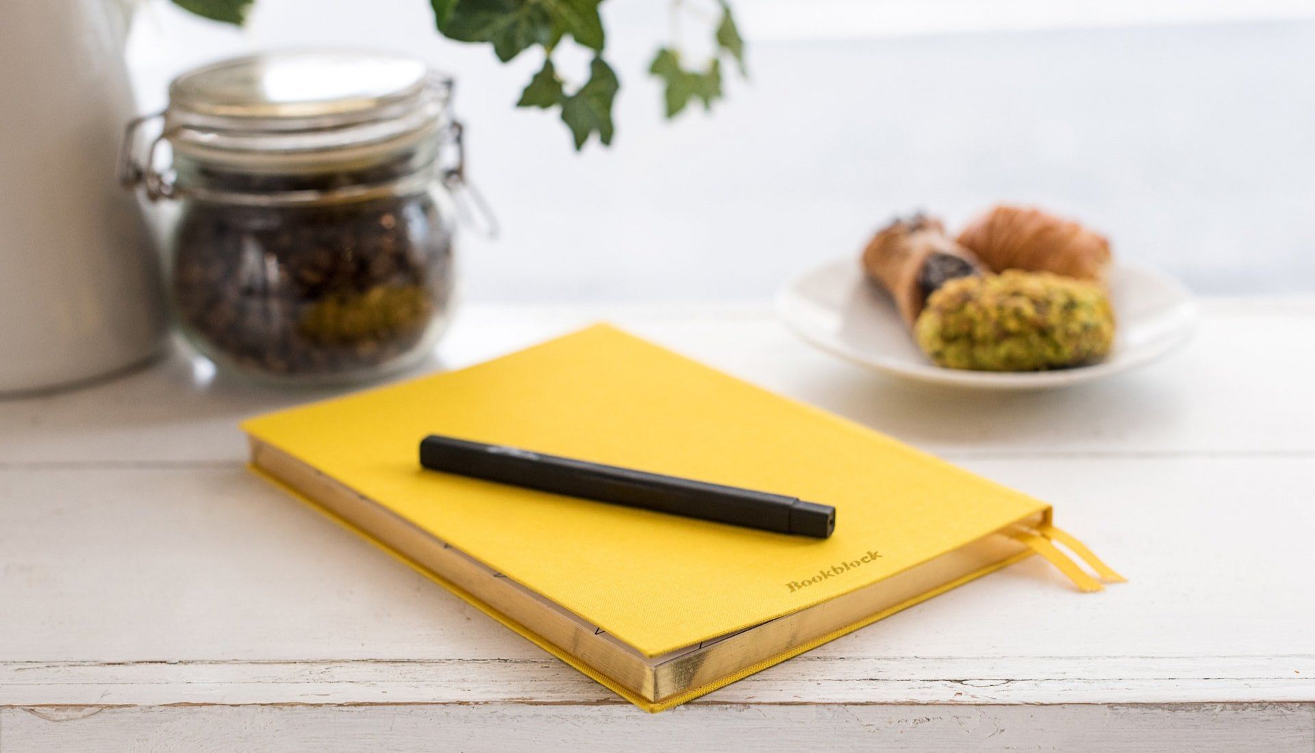 Yellow notebook with a pen and a plate of food on a table
