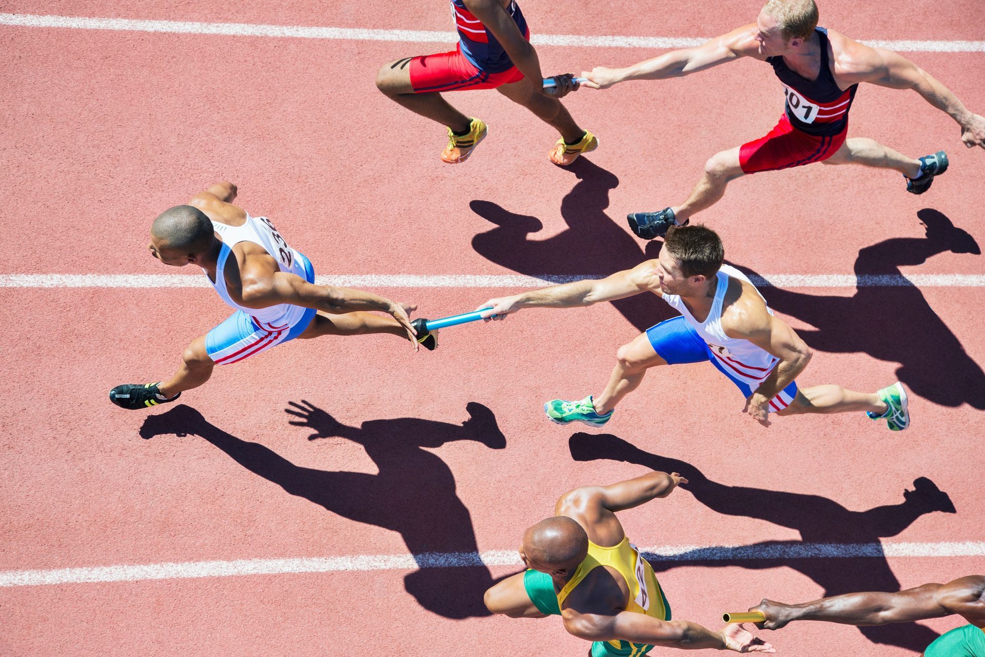 A group of runners are passing a baton on a track.