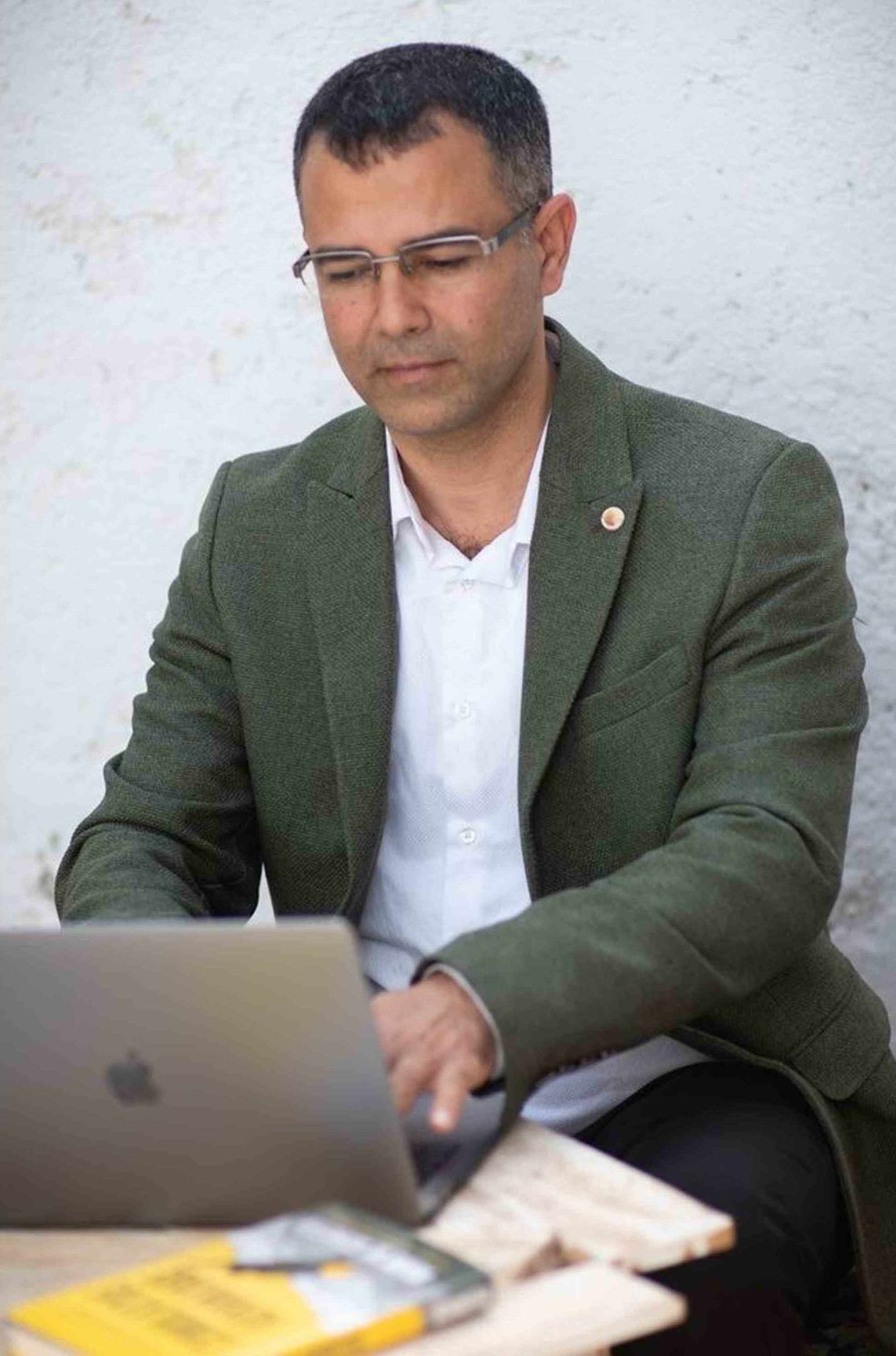 A man sitting at a table using a laptop computer.